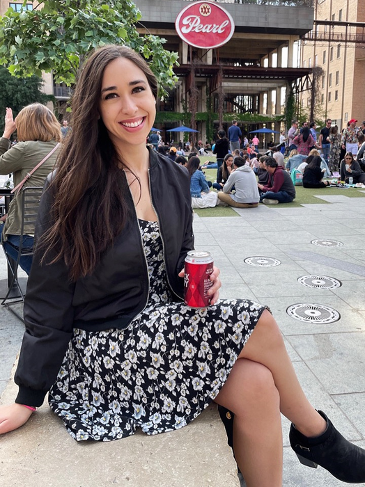 A reviewer shows off a black jacket paired with a floral dress.