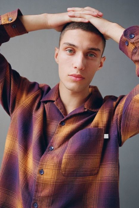 Another model in a purple and mustard plaid shirt that combines vibrant hues effortlessly