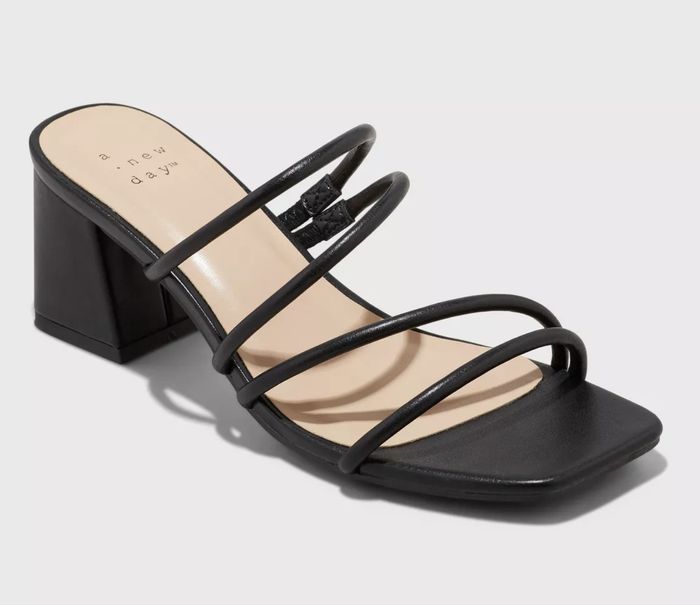 Black strappy heeled sandal presented against a neutral backdrop