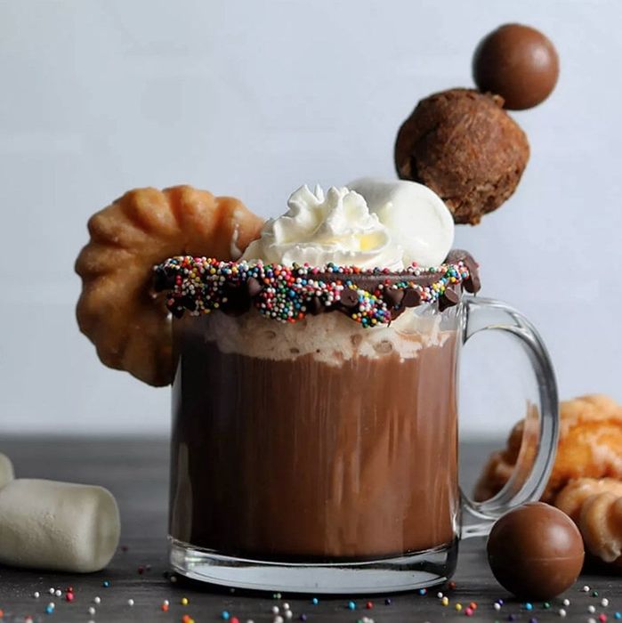 A steaming cup of hot cocoa topped with a swirl of whipped cream