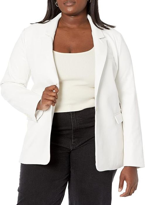 A woman dons a white blazer over a white top and black pants, completing a clean, polished look.