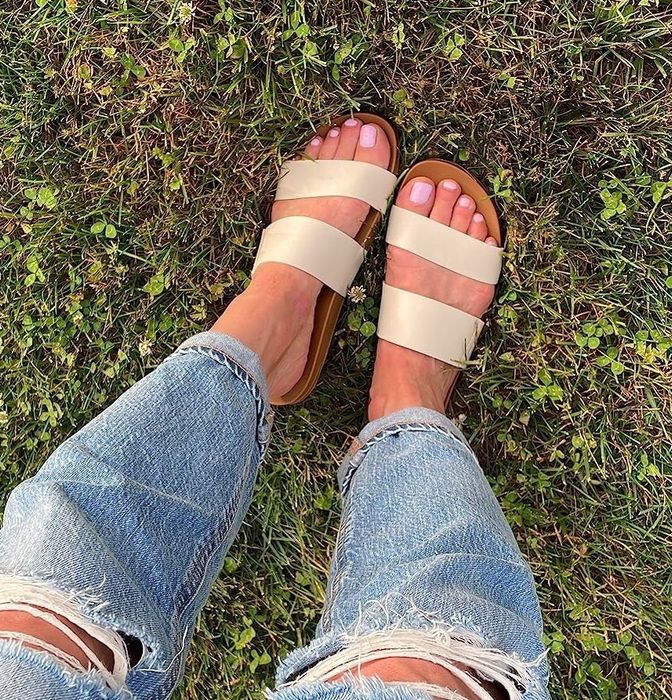reviewer photo of someone wearing distressed jeans with tan sandals, standing on grassy ground