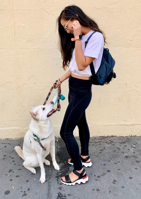 Photo of a reviewer standing with their dog, wearing black and white sandals