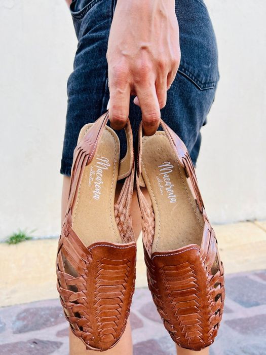 model holding a pair of brown huaraches