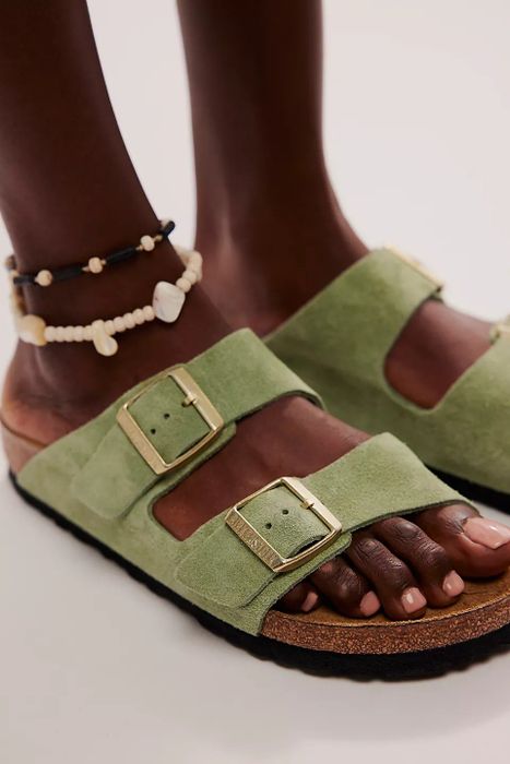 Close-up of someone wearing green suede slip-on Birkenstocks