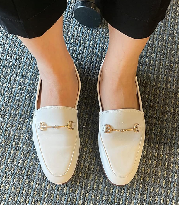 A reviewer showcasing white loafers.
