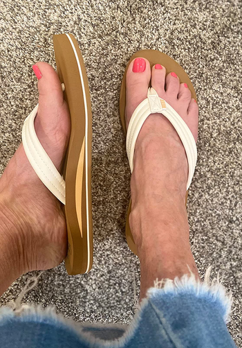 reviewer showcasing a side view of white flip-flops