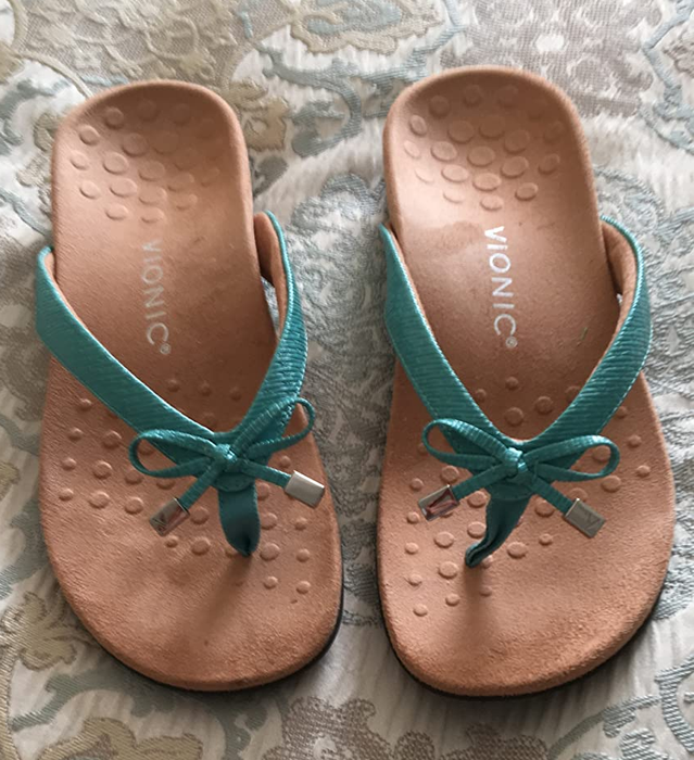 Photo of a reviewer showcasing sandals in a green and tan combination.
