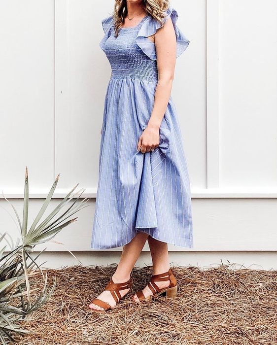 A reviewer sporting a pale blue and white vertical striped dress, paired with tan heels.