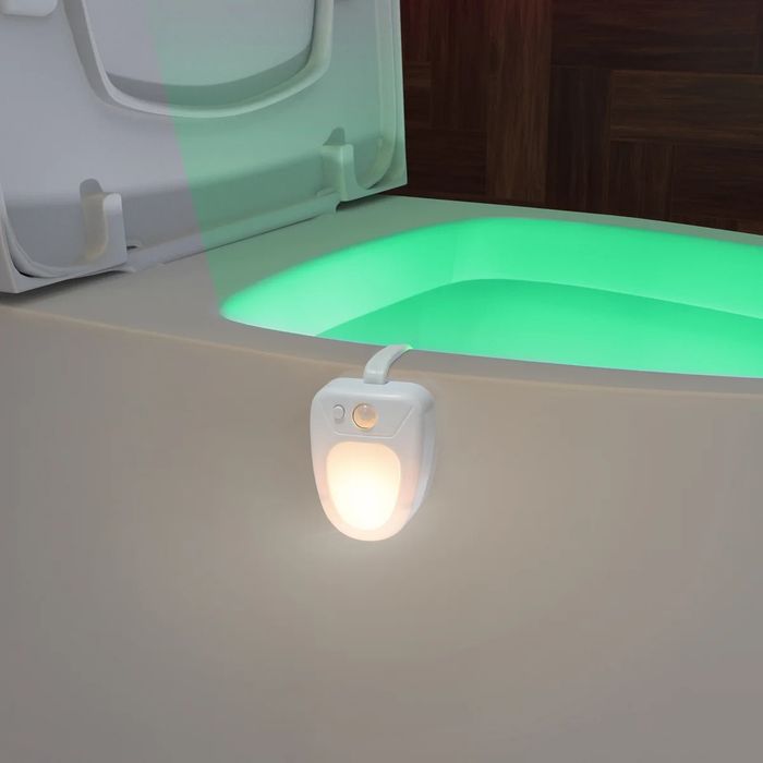A motion-activated night light attached to a toilet, casting light on the bowl for enhanced bathroom safety and convenience during the night.