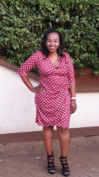 A reviewer is seen wearing a red wrap dress adorned with white polka dots all over.