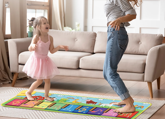 A child happily playing on a colorful step piano mat.