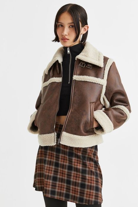 Model rocking a brown leather jacket featuring a cozy cream fleece lining