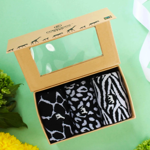 A box containing three black and white socks, each showcasing a unique animal pattern.
