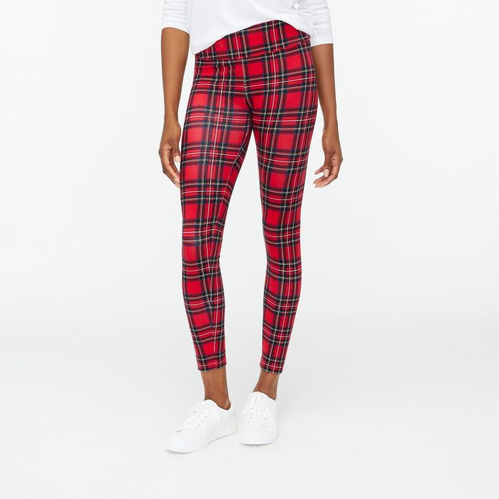 A model wearing red, green, and white plaid leggings paired with a white shirt and shoes