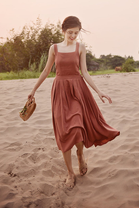 A model wearing a sleeveless, square-neck rust-colored midi dress.