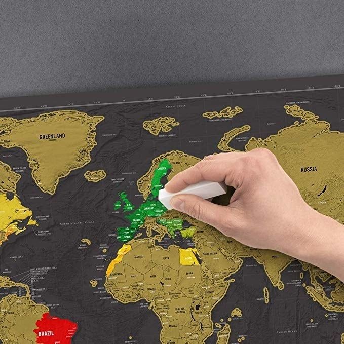 A hand scratching off the gold coating over countries in Europe.