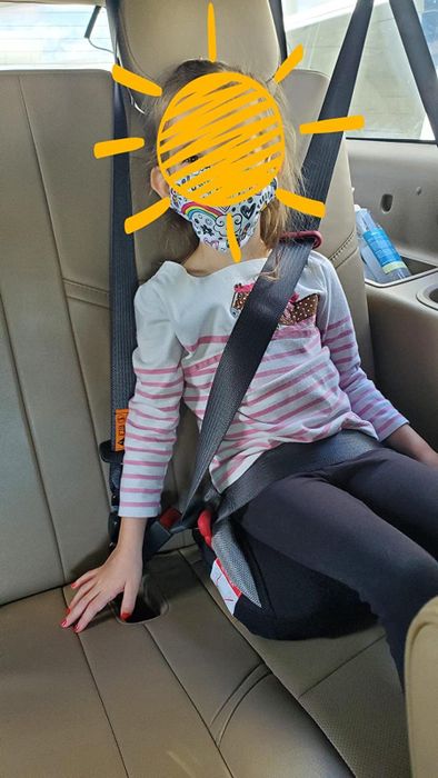 Reviewer’s photo of a child comfortably seated using the booster seat in a car