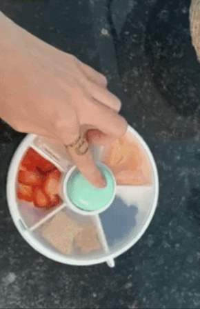 GIF of the reviewer pressing the center button of the snack container, demonstrating how the lid rotates to always keep one section open