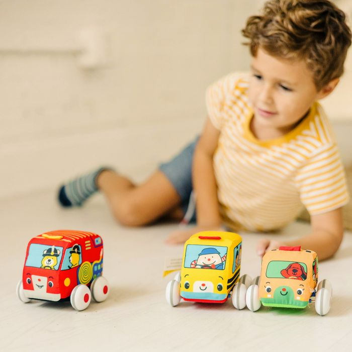 A boy playing with three small cars