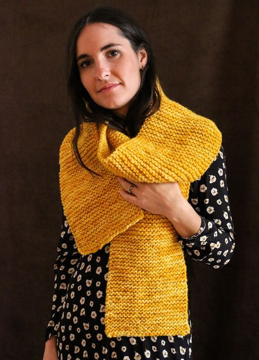 Model wearing a vibrant yellow scarf they knitted themselves