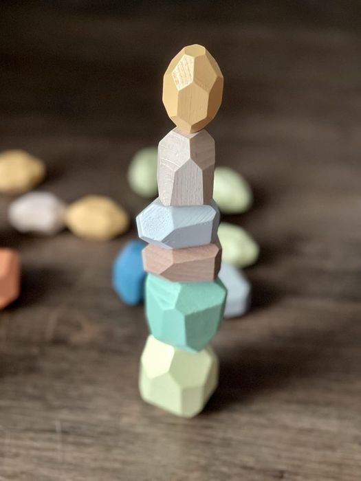A stack of geometric wooden blocks balanced on top of each other on a wooden surface.