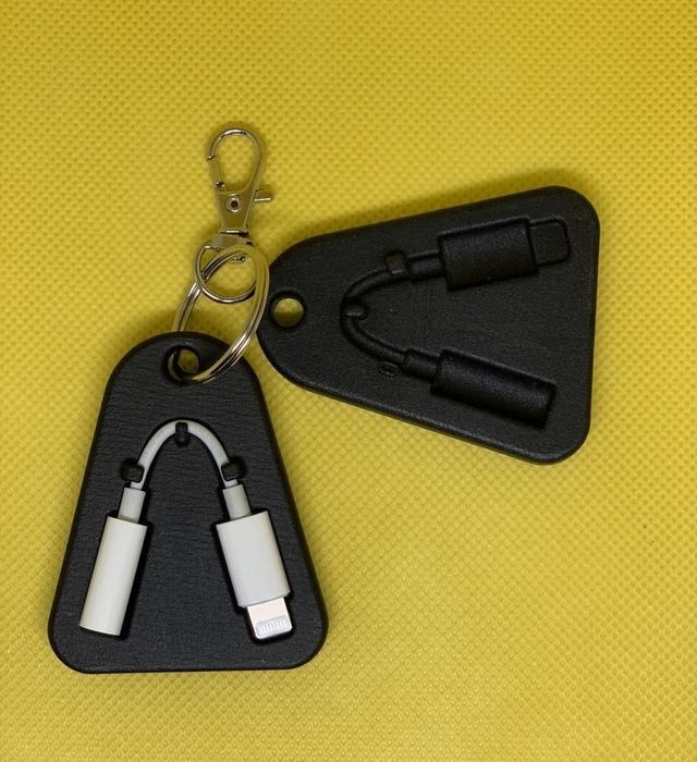 Two sleek black, flat, triangular cases with a slot for a dongle, one holding the dongle and clipped to a keyring.