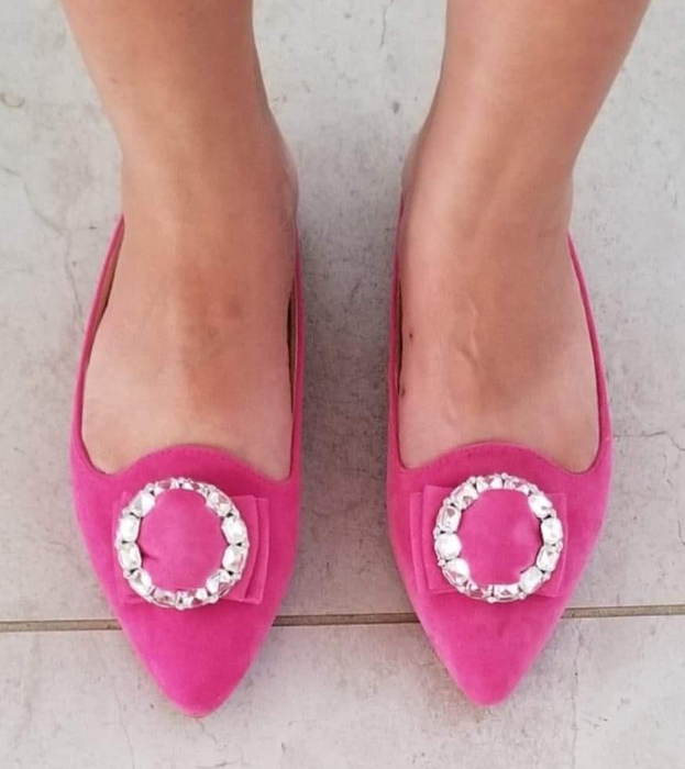 Reviewer wearing pink suede-like pointed-toe slip-on flats with circular embellishment on the top.