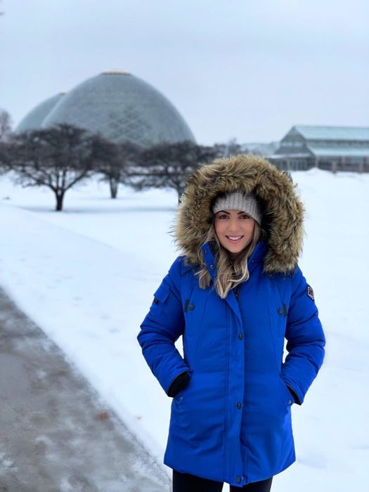A reviewer wearing the blue jacket with the faux fur hood pulled up