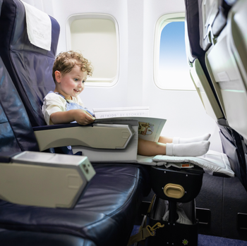 Image of the JetKids suitcase placed in front of an airplane seat, creating a leg rest for added comfort