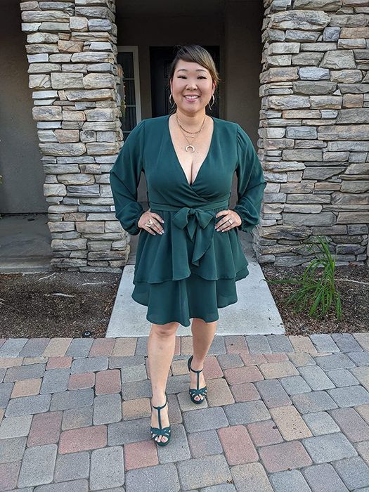A reviewer is seen wearing the wrap dress in a stunning emerald green shade.