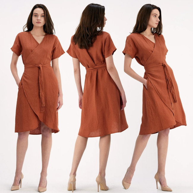 The model is wearing the short linen wrap dress in burnt orange, paired with nude heels.