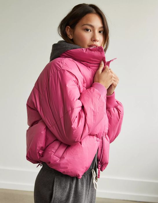 A model in a cozy pink puffer coat.