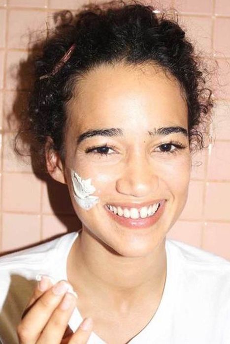 A model with a clay mask applied to their cheek.