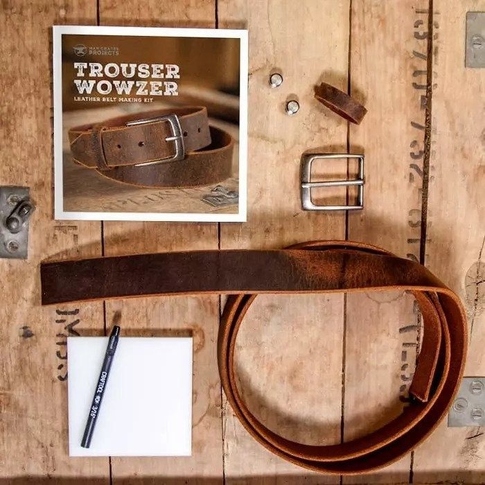 A worn leather strip, a metal buckle, a leather attachment, two metal fasteners, and a set of instructions.