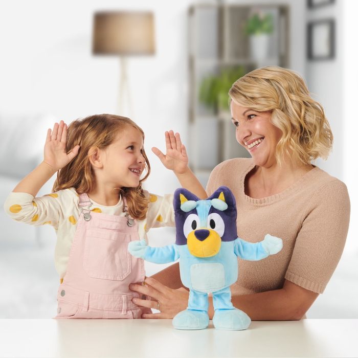 A parent and child having fun together while interacting with a Bluey toy.