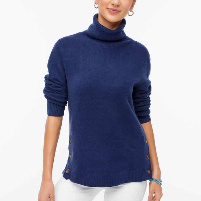 A model wearing a blue turtleneck sweater with stylish button details