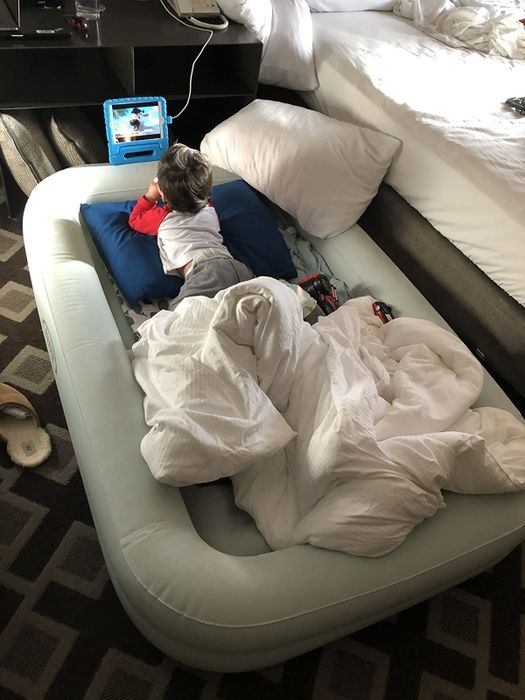 Child enjoying a tablet in the inflatable travel bed