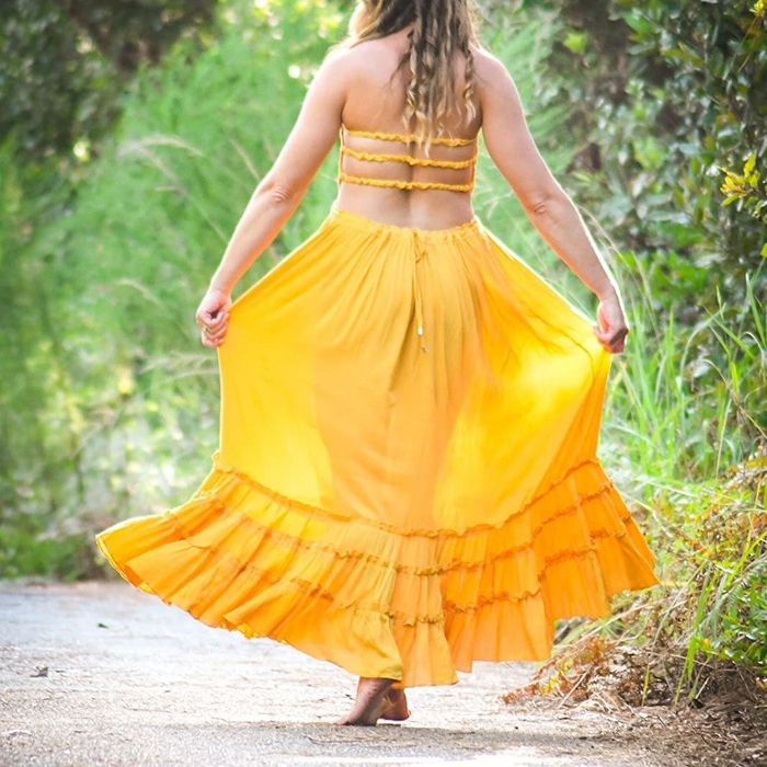 A reviewer wearing a mustard-colored dress, showcasing the backless straps.