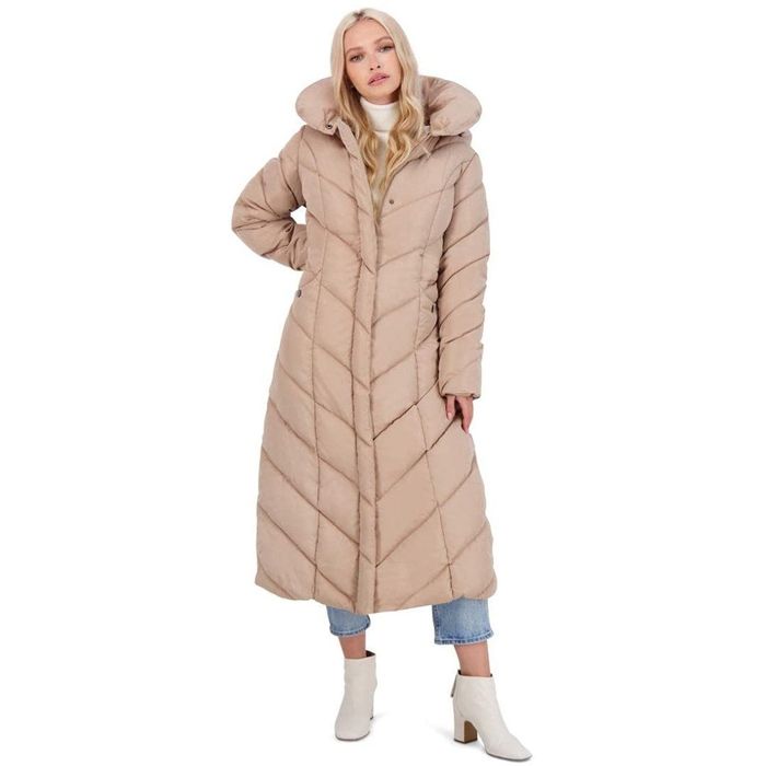 A model with the coat zipped up, showcasing the chevron design in a soft tan shade