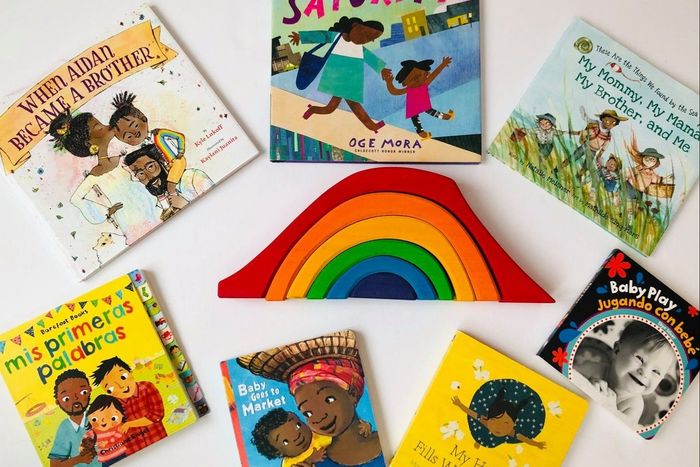 A vibrant assortment of children's books is displayed around a wooden rainbow toy. Titles include