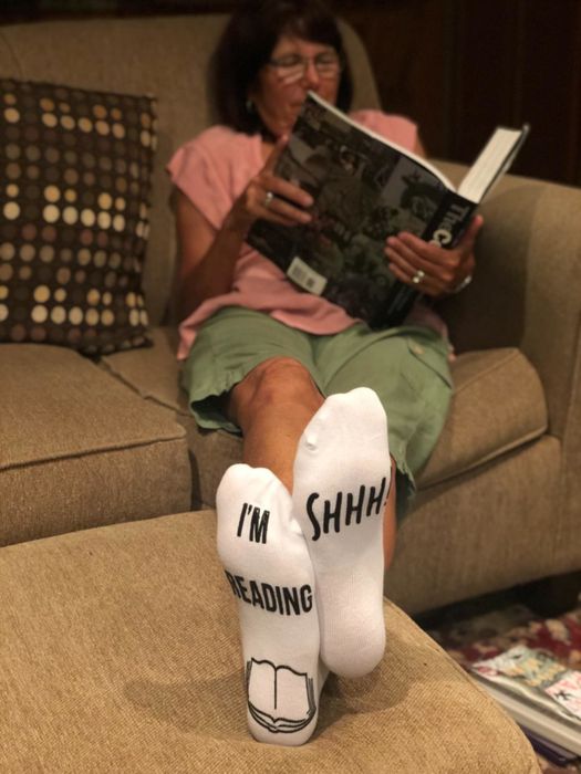 A reviewer’s photo of their mom wearing the socks while reading a book