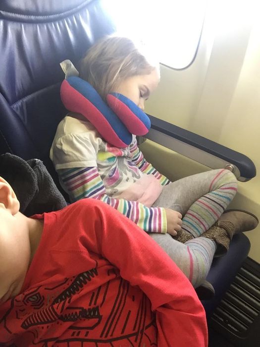 Image of a child sleeping on a plane with the neck pillow on