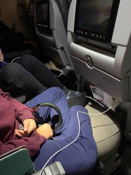Image of the footrest placed between airplane seats, providing a child with a comfortable place to relax