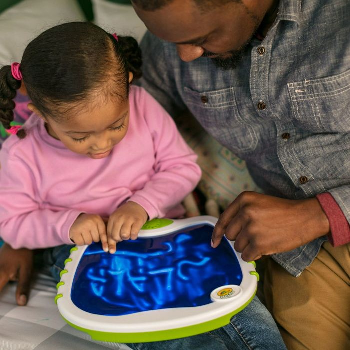 A parent watching their child color on a doodle pad