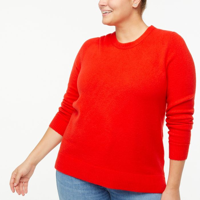 Model showcasing a red sweater paired with blue jeans