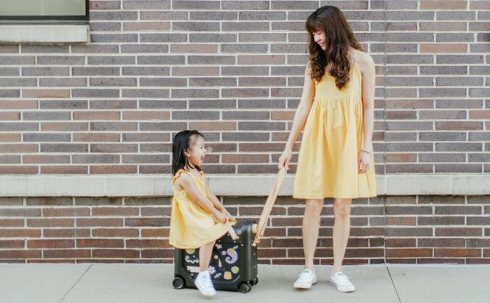 Model demonstrating how a child can sit on the rolling suitcase