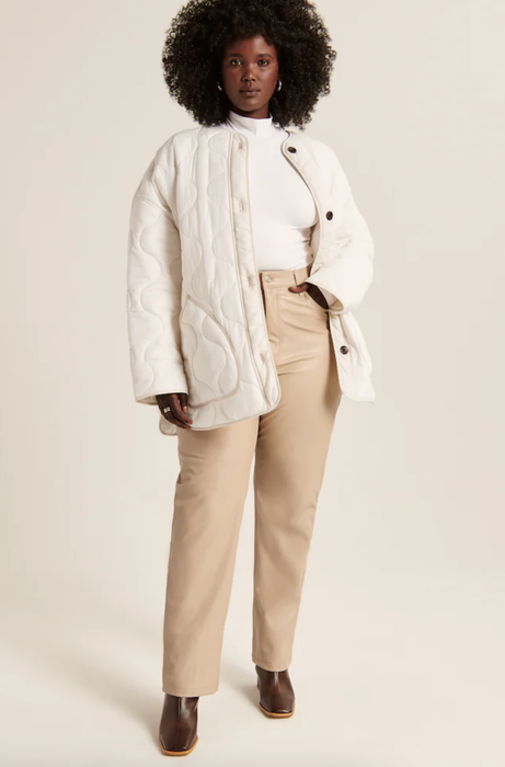 Model wearing a white quilted jacket, hand casually placed in the pocket