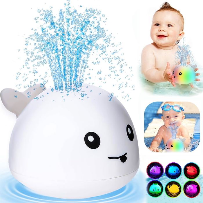 A baby having fun playing with a color-changing whale toy in the water.