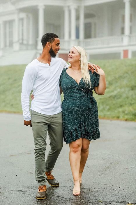 A reviewer is wearing the short wrap dress in a deep green color, dotted with tiny white accents.